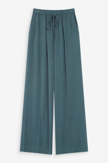 Pantalon large émeraude sur fond neutre avec coupe fluide