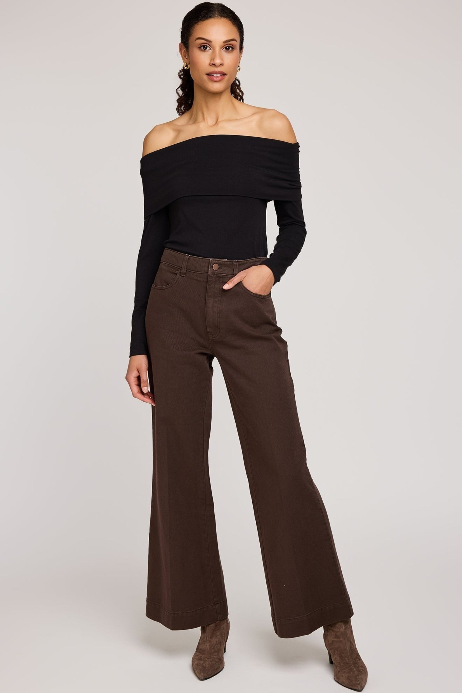 Femme portant le pantalon Polly brun avec un haut noir épaules dégagées, vue complète du look.