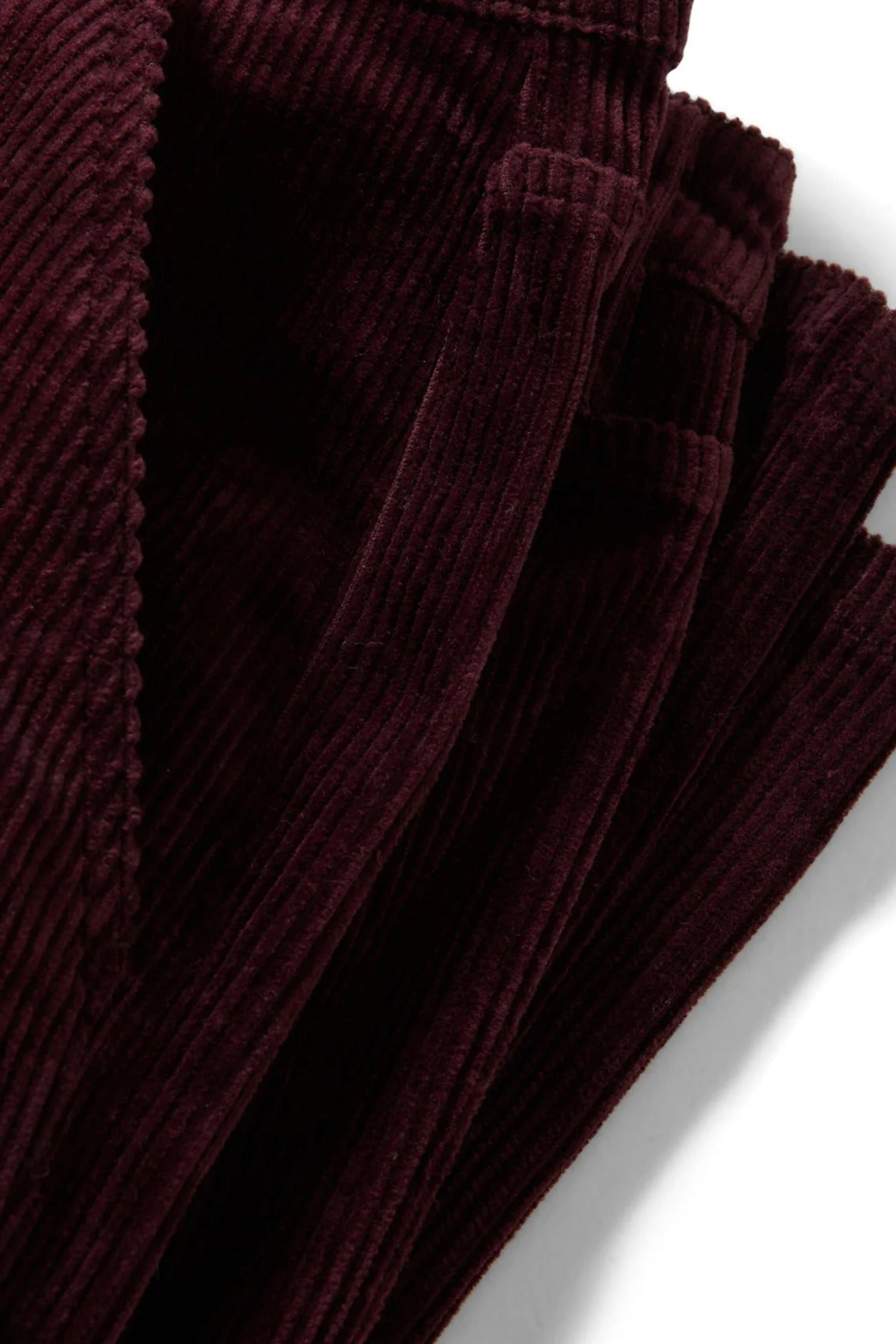 Détail de la jambe en velours côtelé bourgogne, coupe décontractée avec ouverture de jambe large