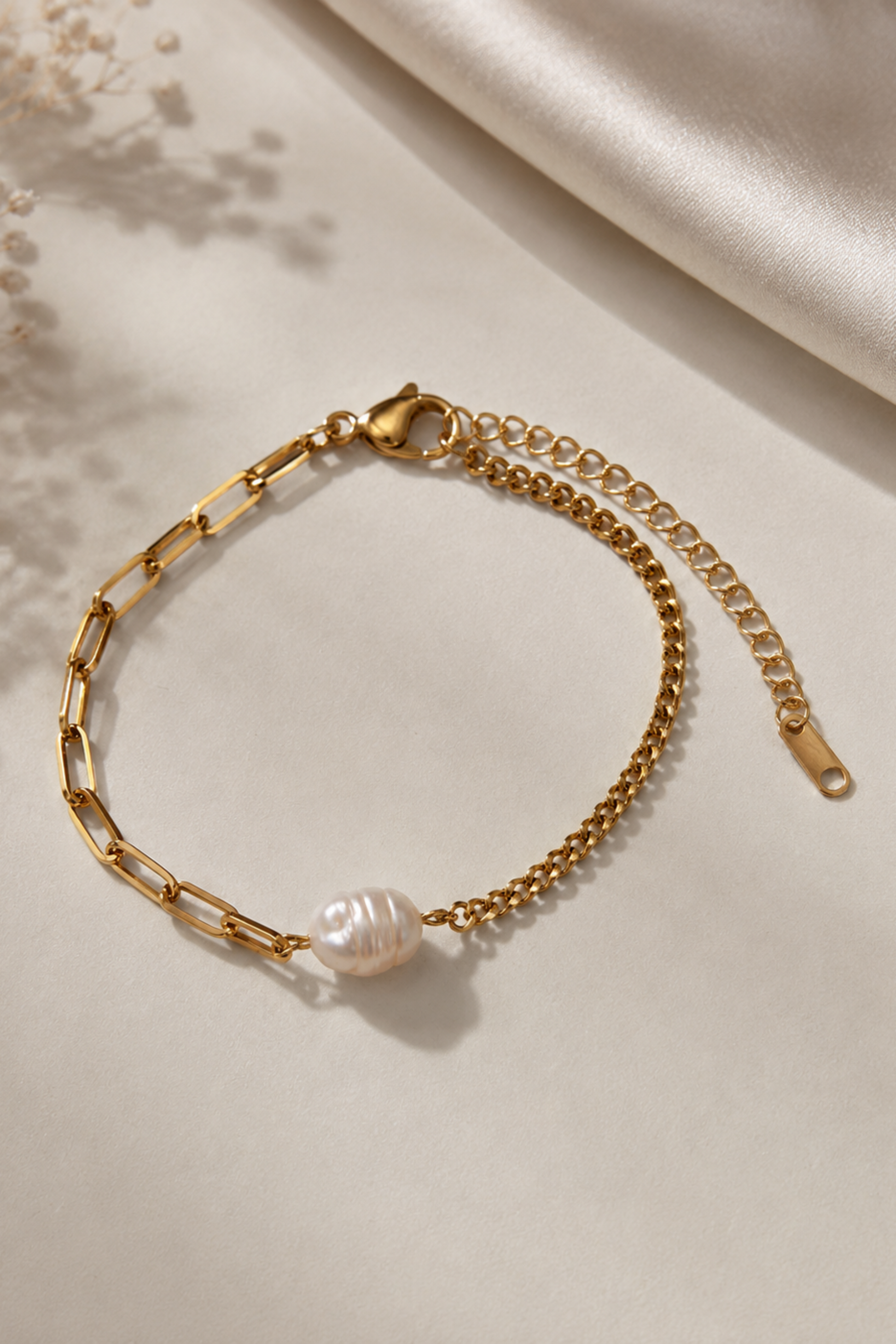 Bracelet Perla Or doré avec perle d’eau douce, chaînes mixtes et fermoir ajustable sur fond satiné élégant.