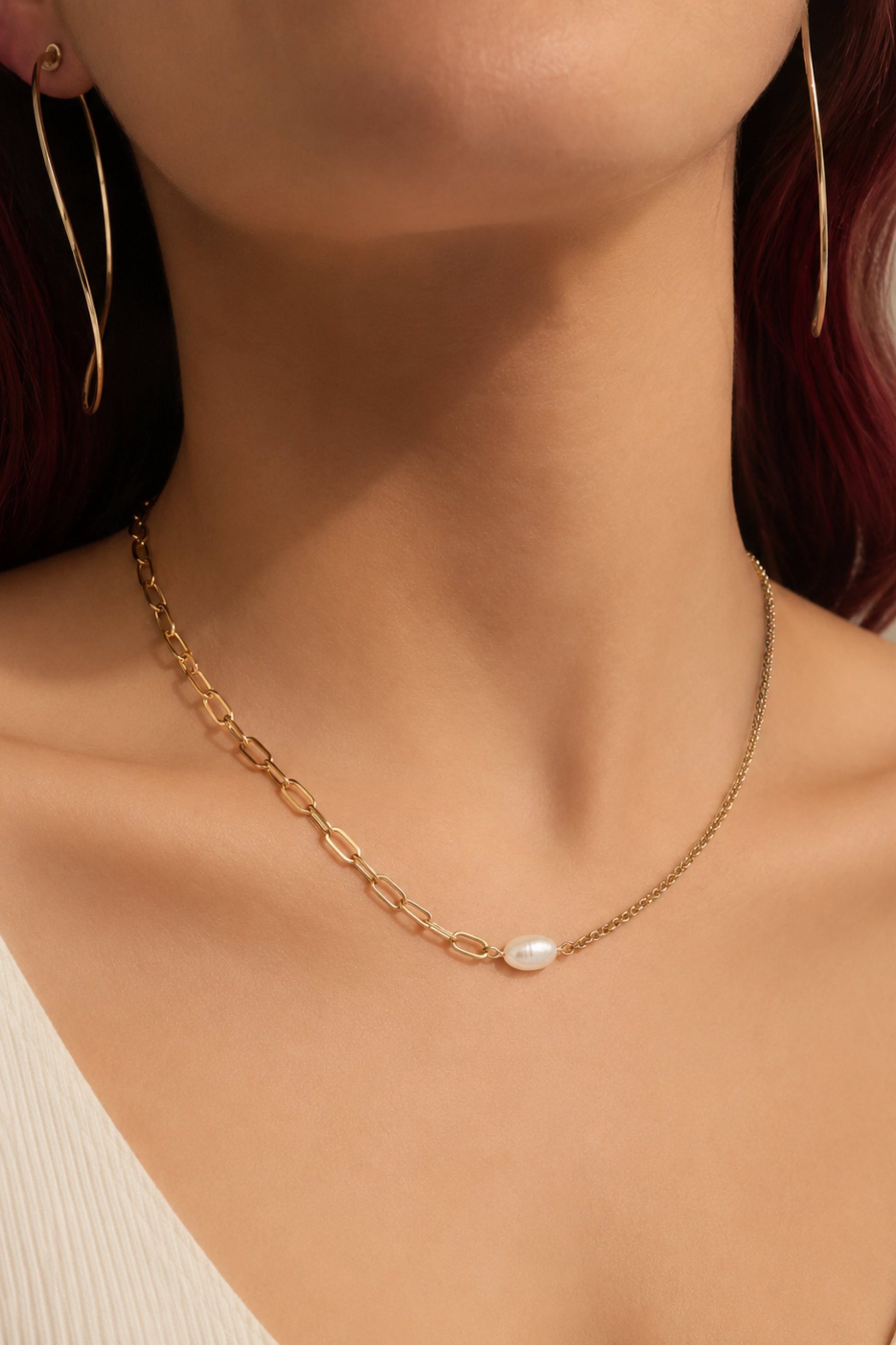 Collier Perla Or porté au cou avec perle d’eau douce centrale et chaîne dorée délicate.