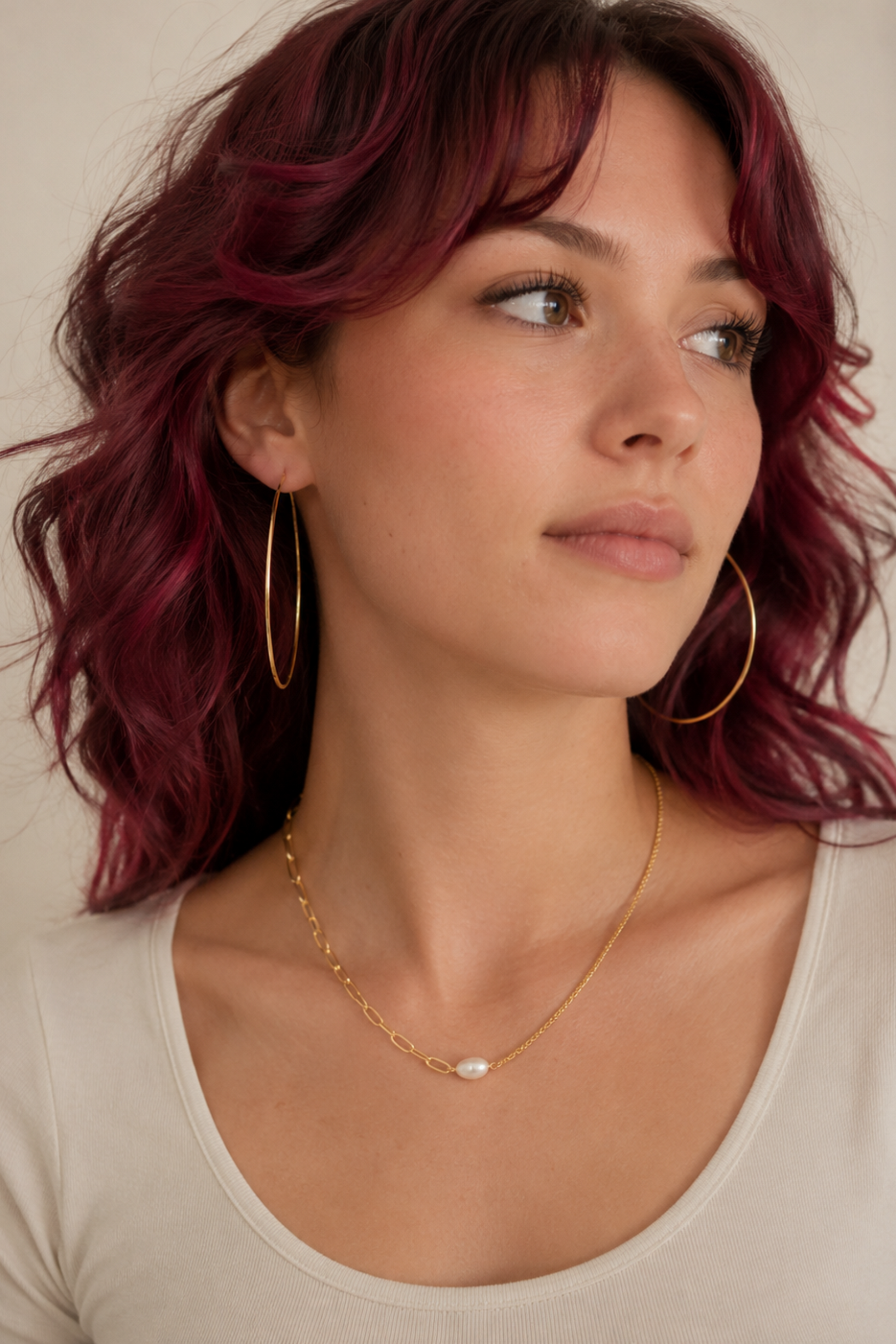 Collier Perla Or porté avec une tenue crème, bijou doré minimaliste avec perle d’eau douce.