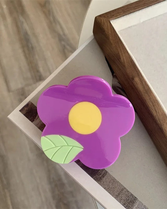 Pince à cheveux en acétate 6 x 7 cm en forme de fleur mauve avec centre jaune et feuille verte, vue de dessus