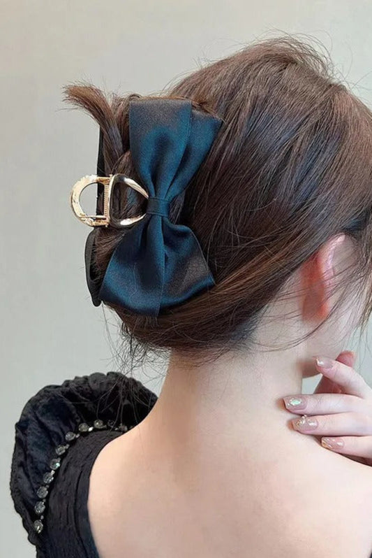 Pince à cheveux chic en satin noir portée, avec grand nœud élégant et pince dorée