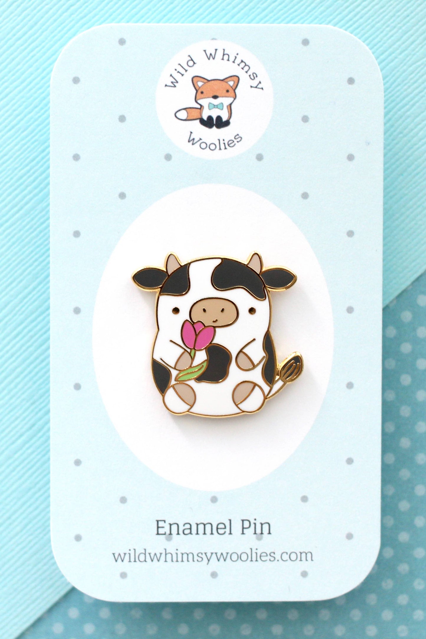 Pin’s en émail vache tenant une tulipe présenté sur carte de support