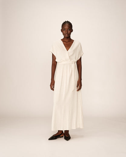 Robe longue beige fluide portée en pied, silhouette féminine et décontractée