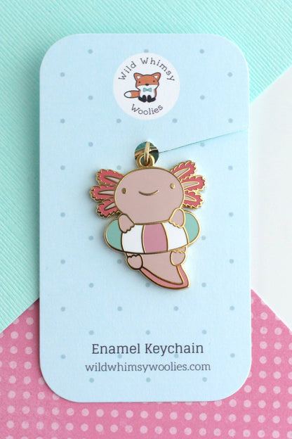 Porte-clés Axolotl Flottant en émail dur doré présenté sur carte bleue, couleurs rose et turquoise.
