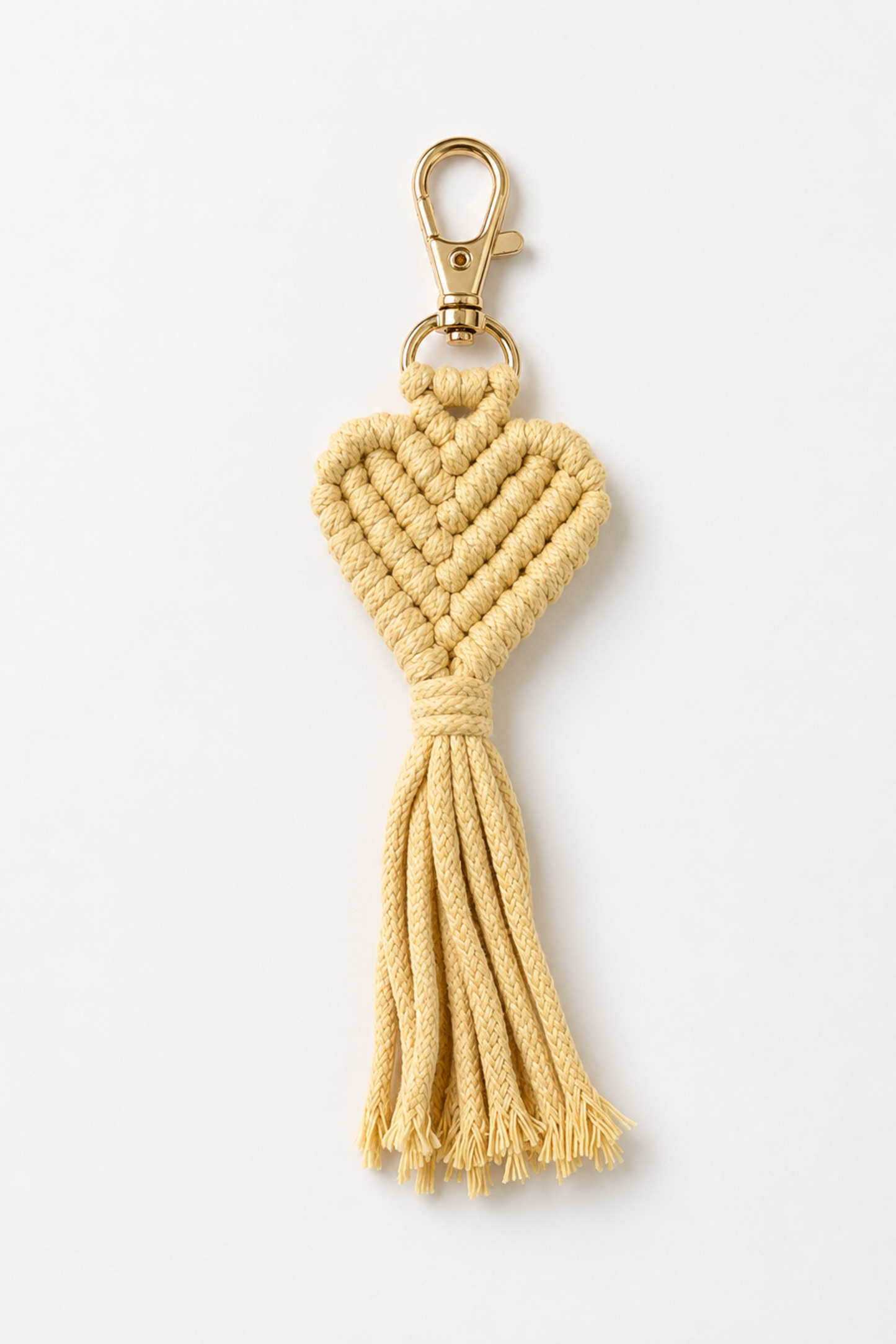 Porte-clé cœur en macramé jaune pâle avec mousqueton doré et finition artisanale.