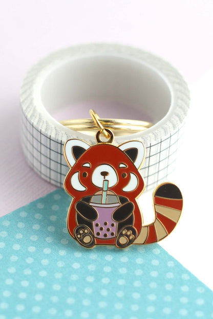 Porte-clés Panda Roux émaillé présenté sur carte bleue Wild Whimsy Woolies – finition dorée brillante