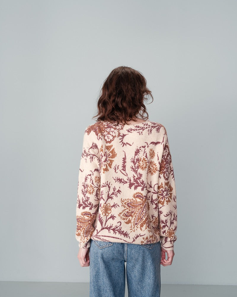 Pull en laine beige fleuri à encolure ronde en laine. Porté avec un jeans par une femme vu de dos.