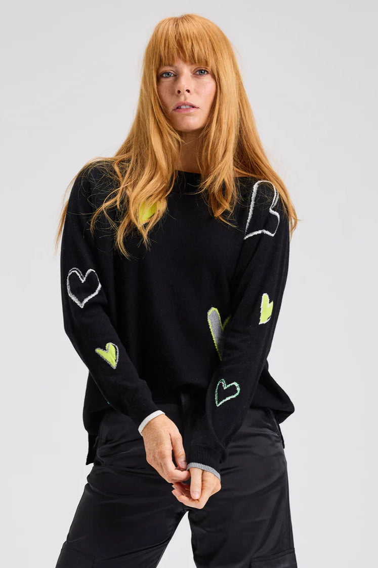 Gros plan sur le pull noir avec encolure bateau et cœurs contrastés

