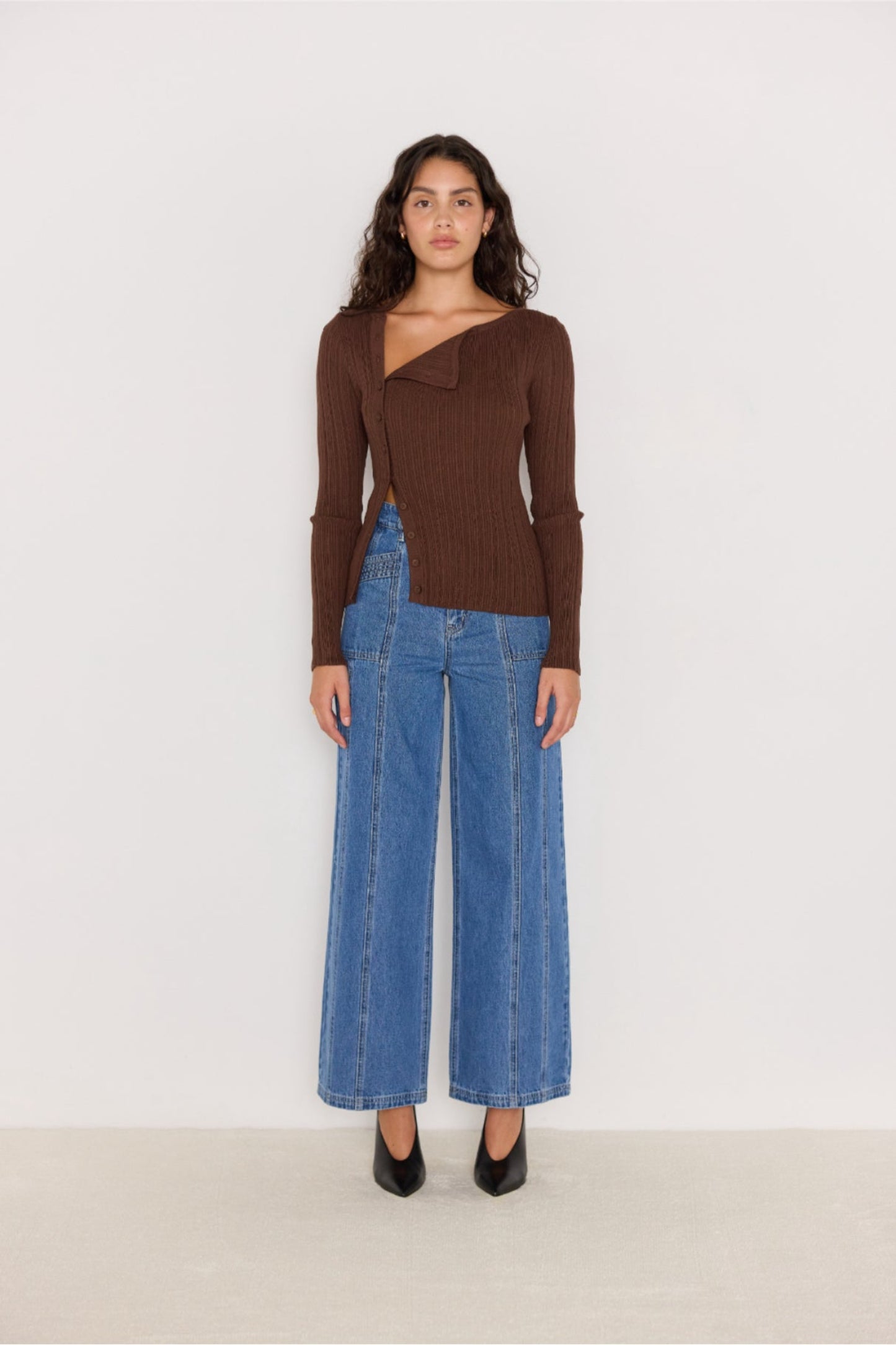 Pull chocolat à col asymétrique porté avec un jean large et escarpins