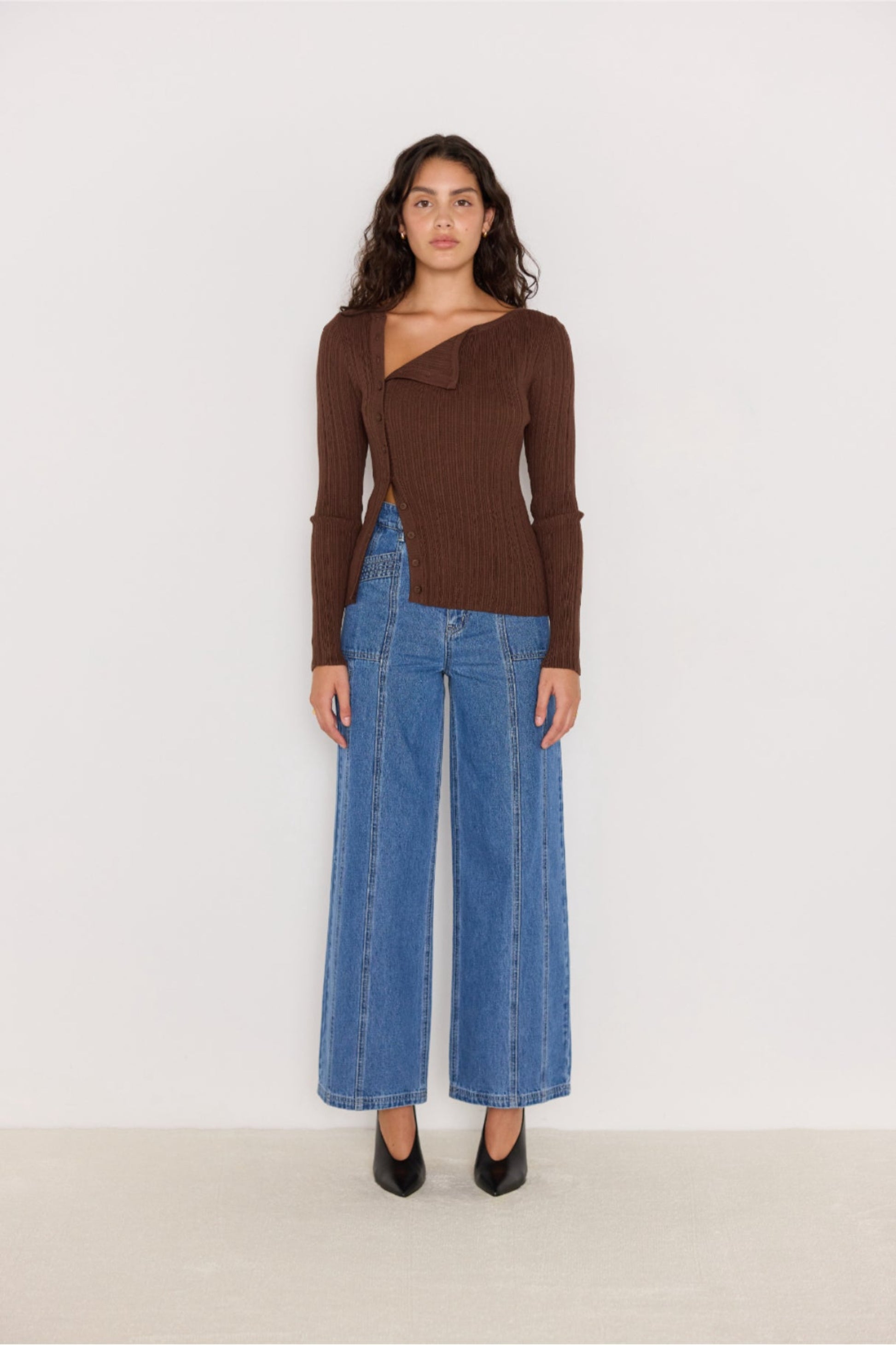 Pull chocolat à col asymétrique porté avec un jean large et escarpins