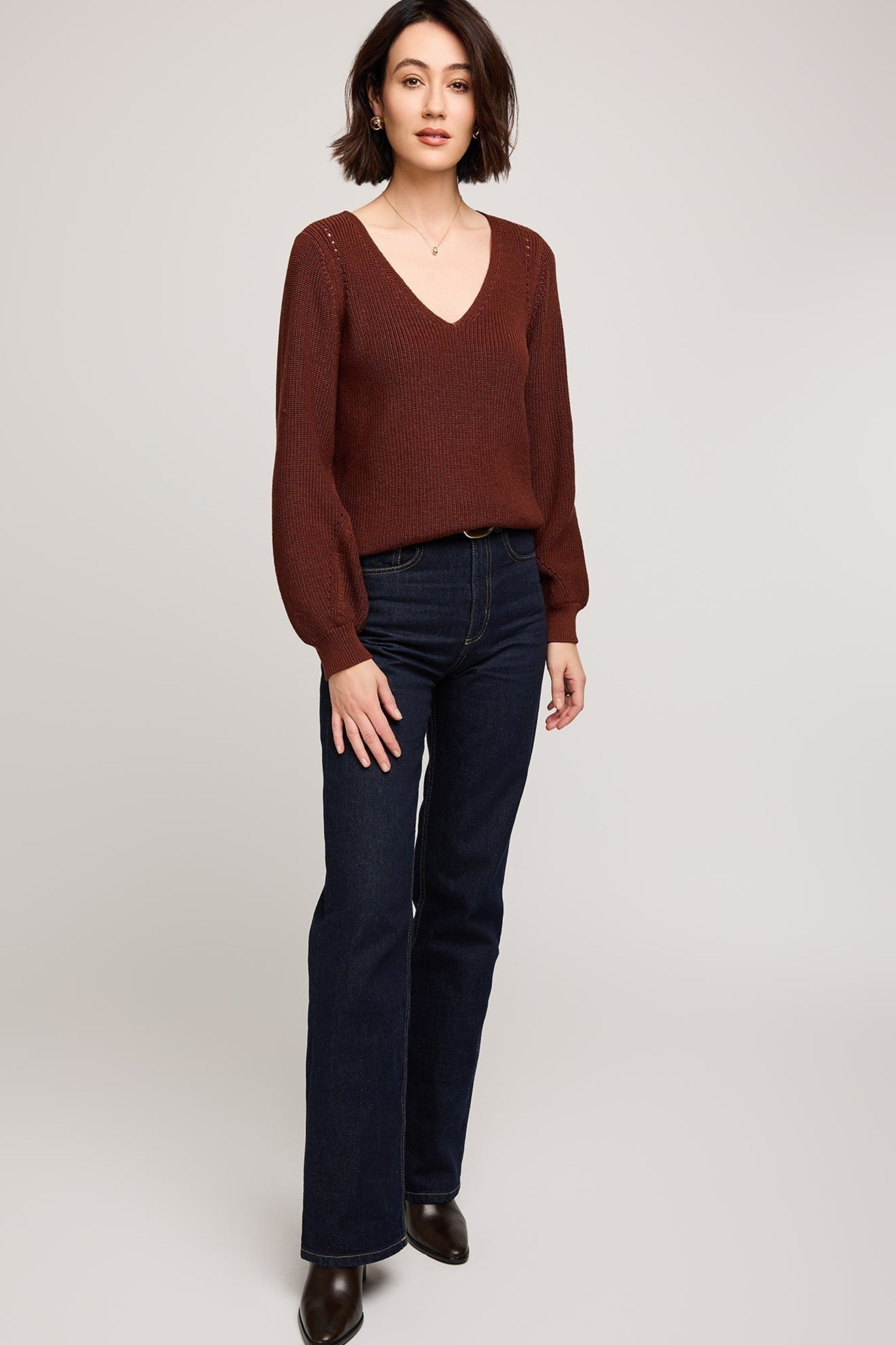 Femme portant le pull Pauline acajou à col en V, vue complète avec jean et bottines.