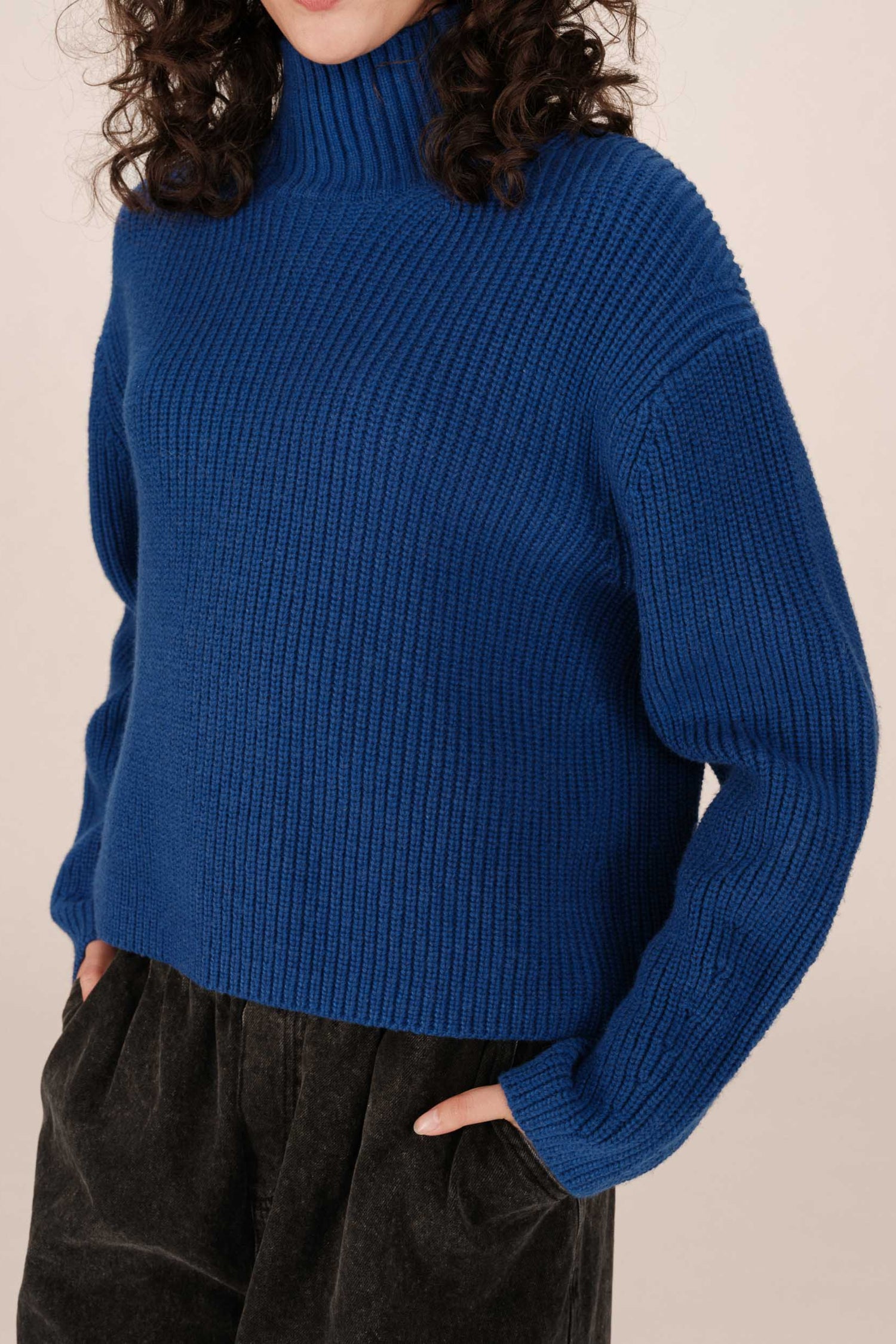 Gros plan du buste du pull Sagan bleu porté - col montant et texture côtelée