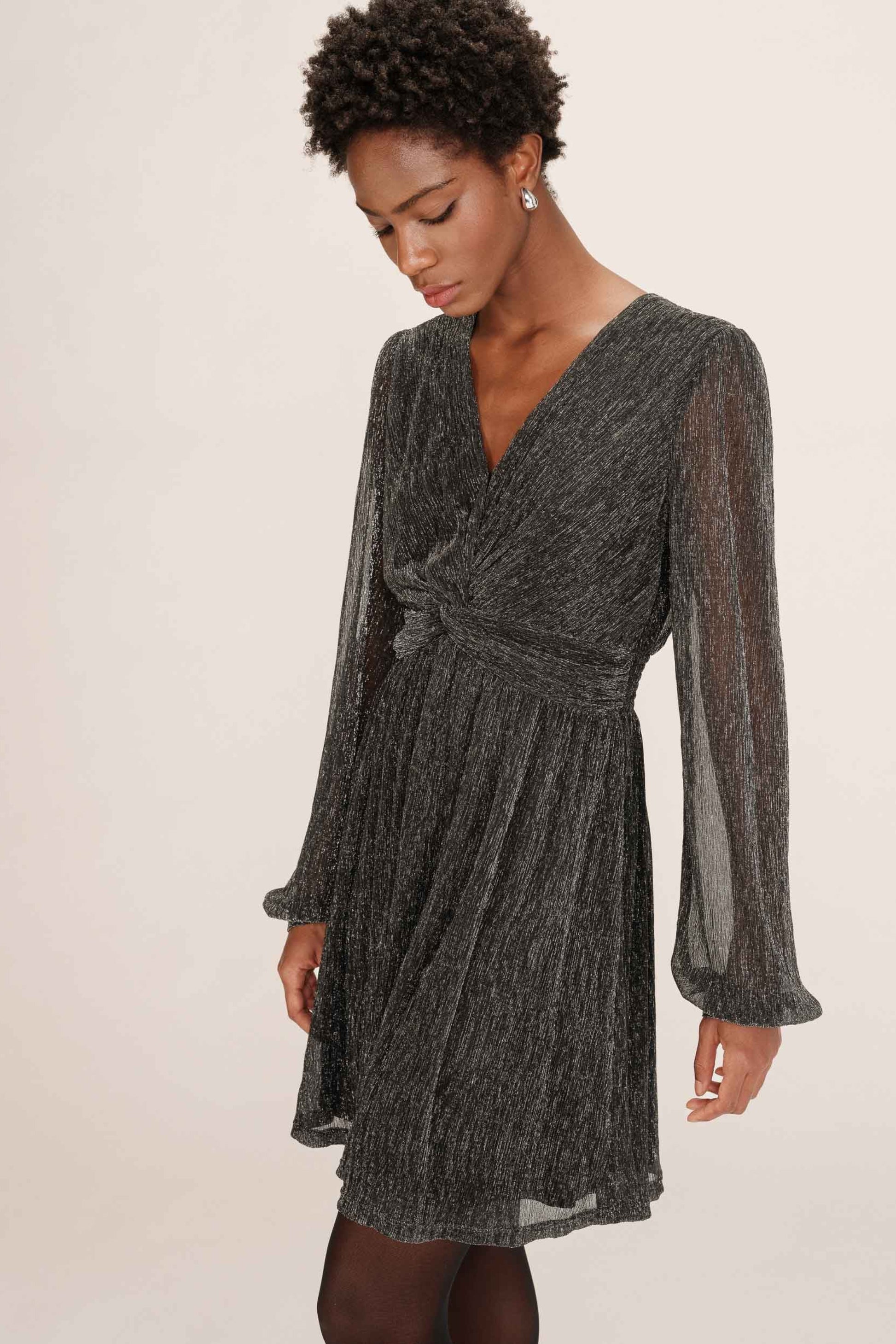 Vue rapprochee du haut de la robe Tina argent avec encolure en V et manches voilees.