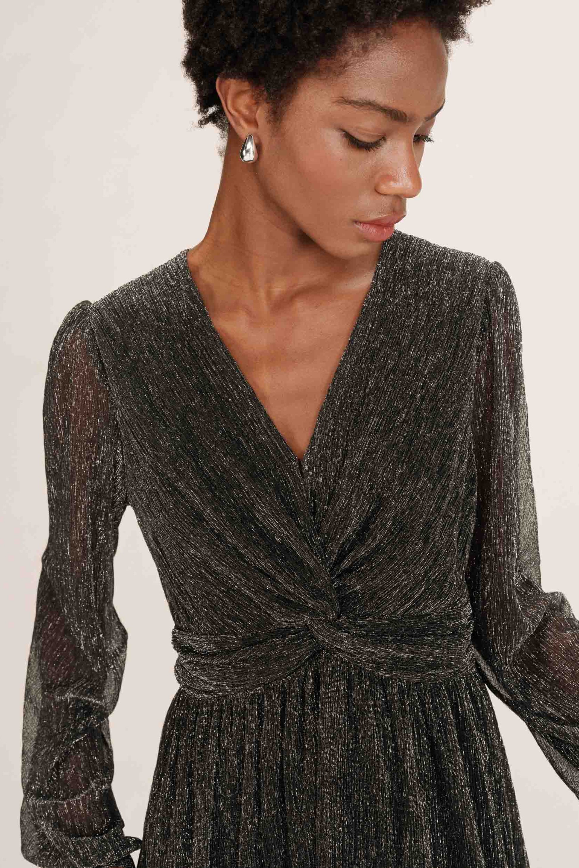 Gros plan sur le noeud a la taille de la robe Tina argent, tissu lurex scintillant.