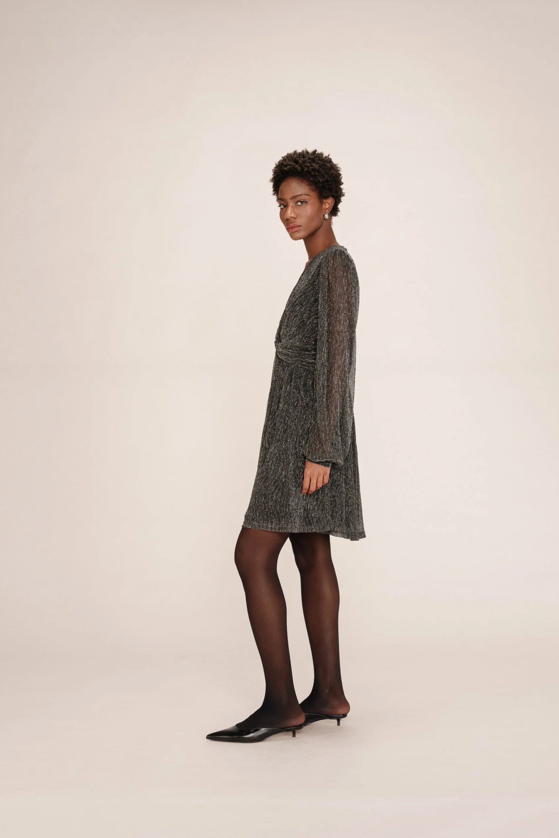 Vue de cote de la robe Tina argent portee, coupe courte evasee.