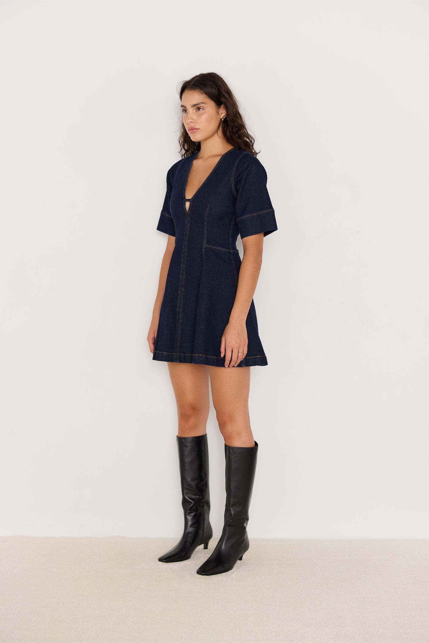 Vue de côté de la robe en denim bleu foncé, col V et coupe évasée
