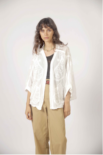 Détail des broderies blanches et des manches fluides du cardigan