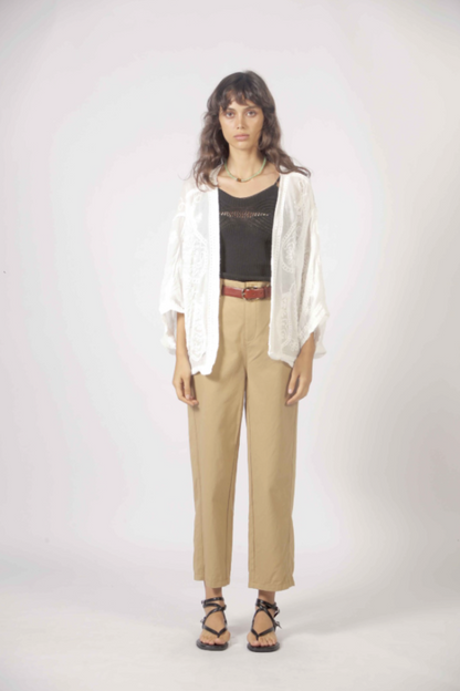 Cardigan blanc brodé porté avec pantalon beige et débardeur noir