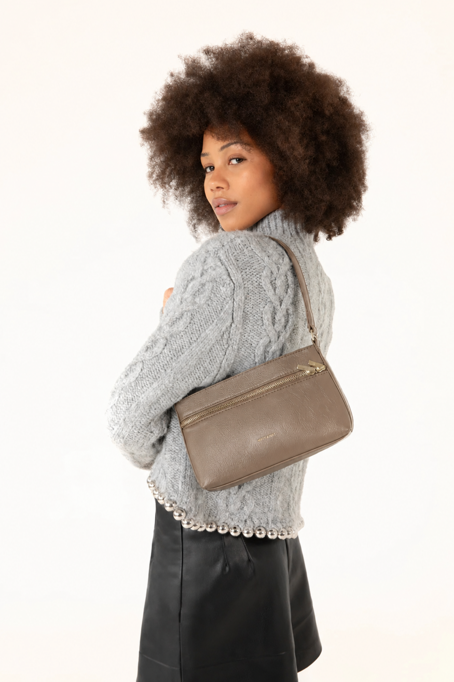 Sac bandoulière Malene Sepia porté à l’épaule avec un tricot gris et une jupe noire, style chic et moderne.