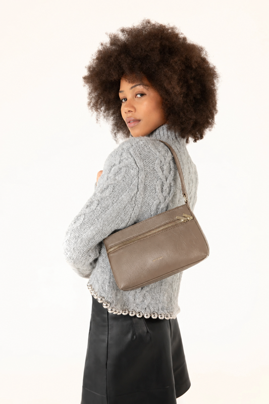 Sac bandoulière Malene Sepia porté à l’épaule avec un tricot gris et une jupe noire, style chic et moderne.