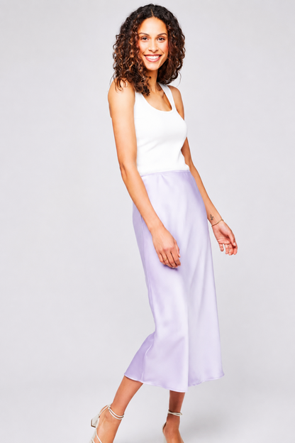 Jupe Selena mauve portée avec une camisole blanche, coupe midi fluide et fini satiné brillant.