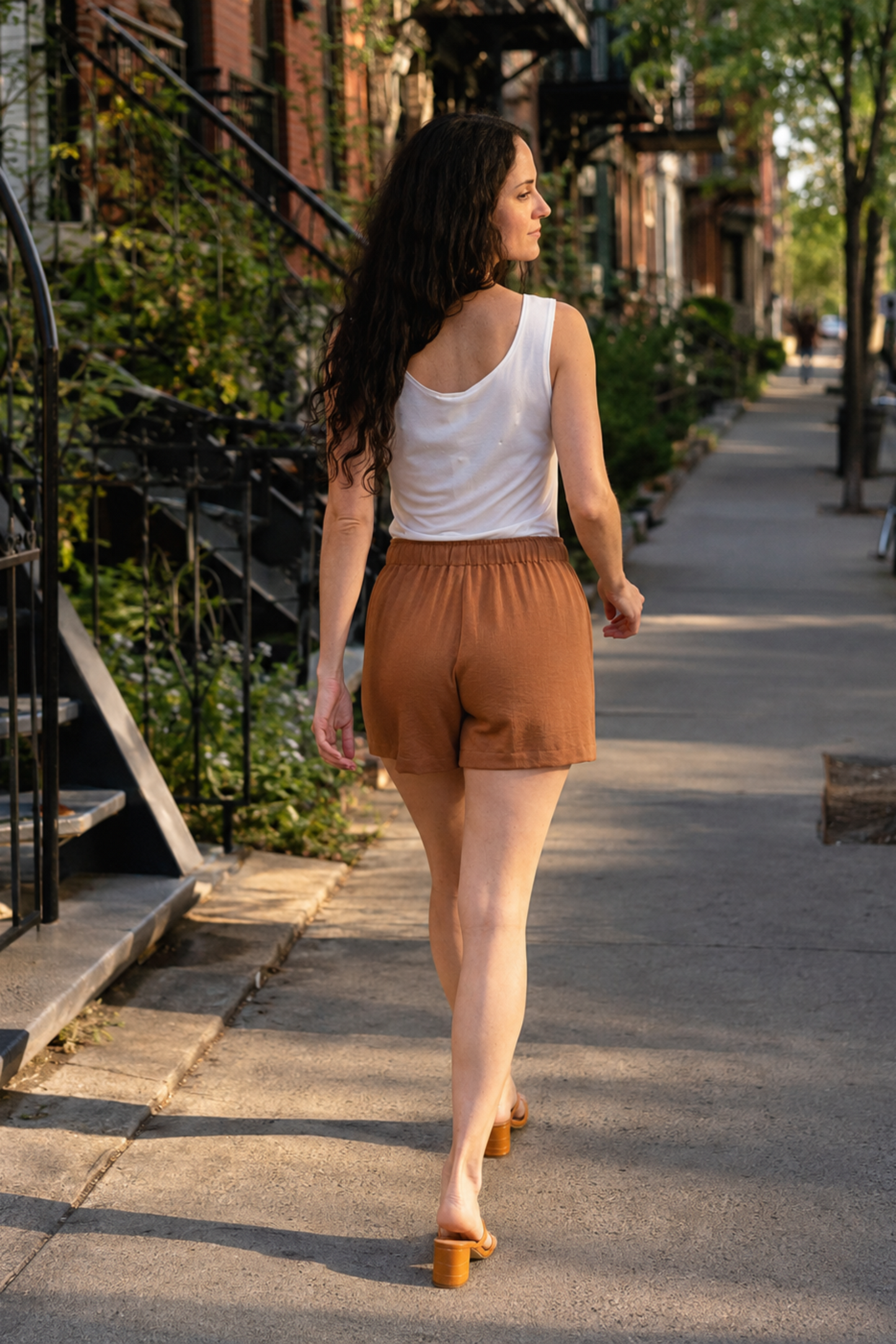 Vue de dos du short camel fluide avec taille élastique, porté dans une ambiance lifestyle estivale à Montréal.