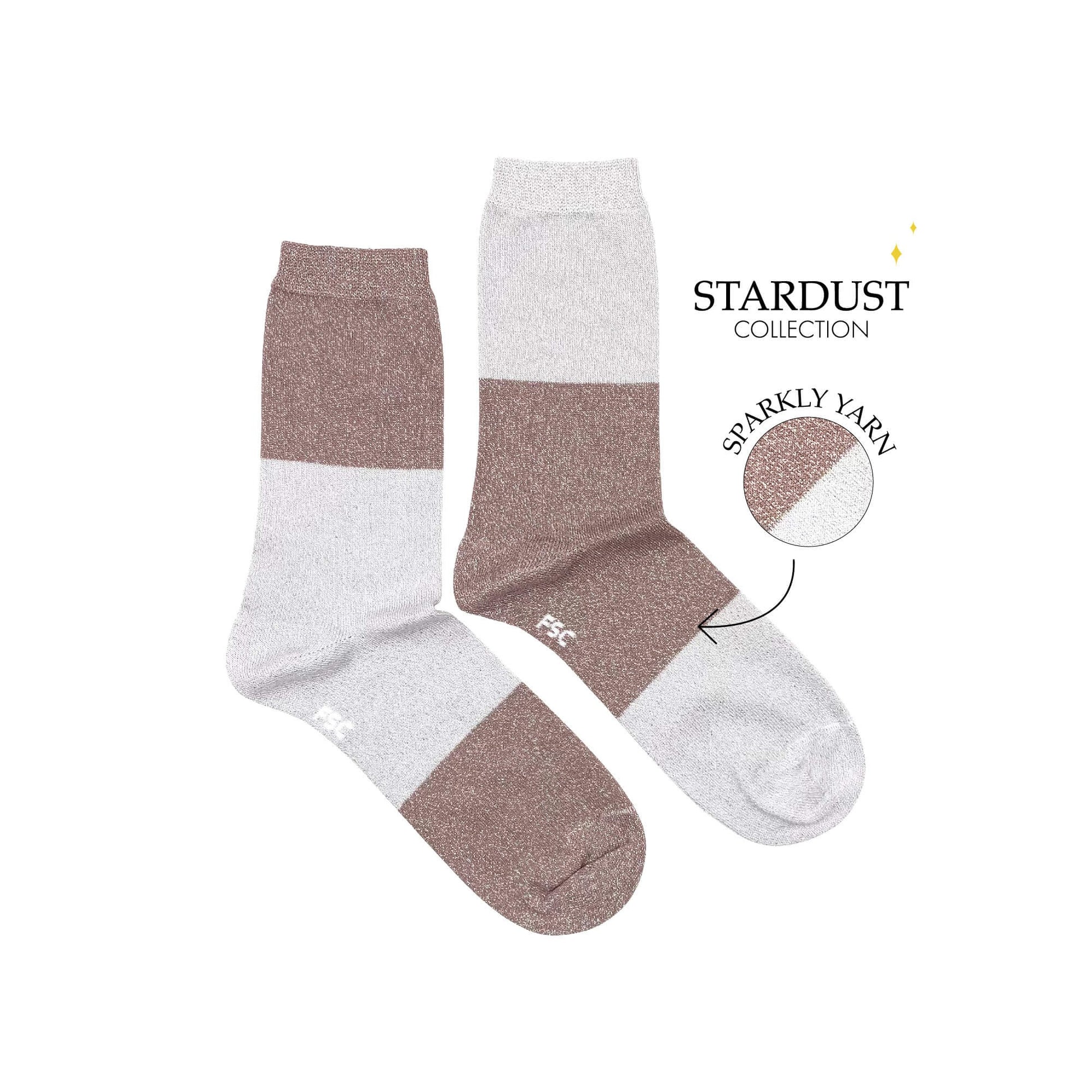 Paire de chaussettes dépareillées sur fond blanc. Les chaussettes sont découpées en trois grosses bandes passant de beige à un rose très pale pour une chaussette et inversement pour l’autre. Ce sont des chaussettes à paillettes.  