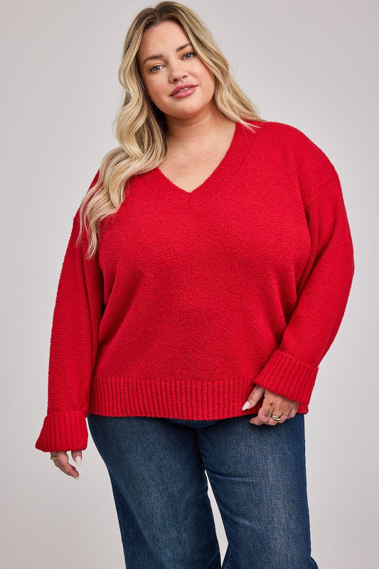 Gros plan sur l’encolure en V et les poignets côtelés du pull rouge coupe oversize