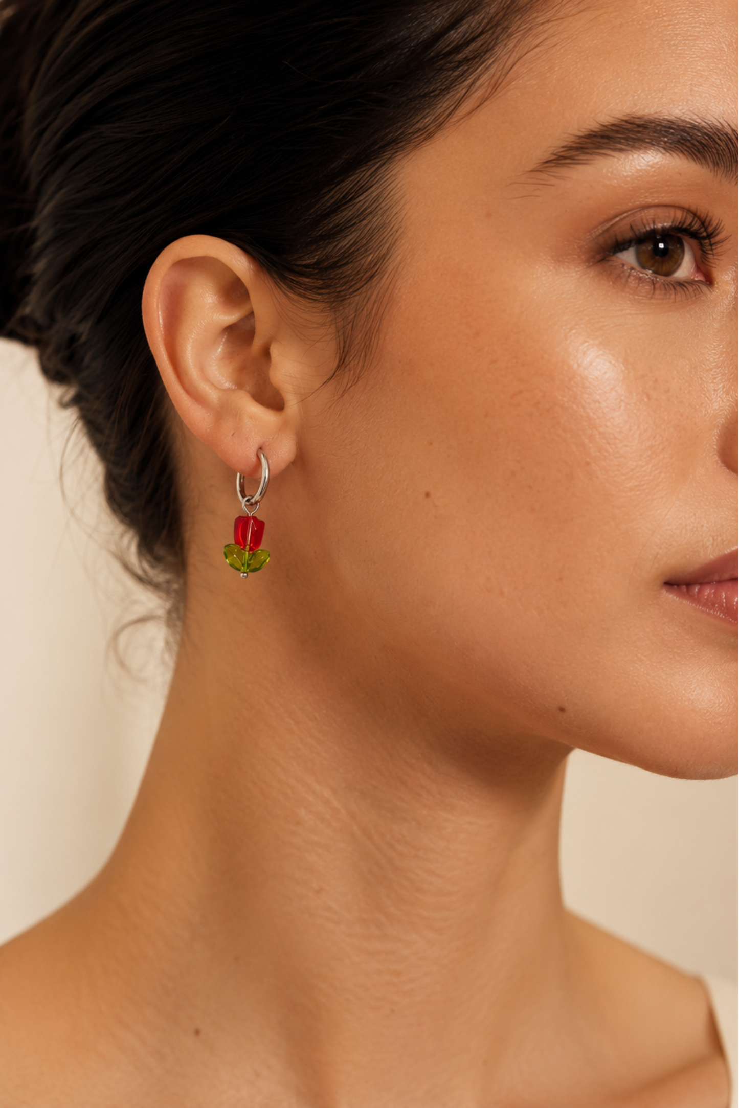 Boucle d’oreille Tulipe portée avec fleur rouge et feuilles vertes, style floral délicat.