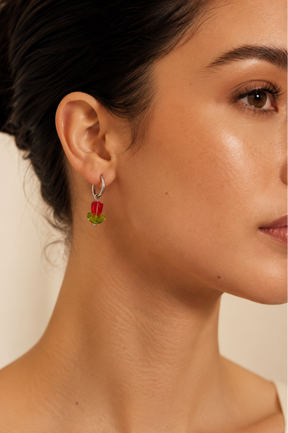 Boucle d’oreille Tulipe portée avec fleur rouge et feuilles vertes, style floral délicat.