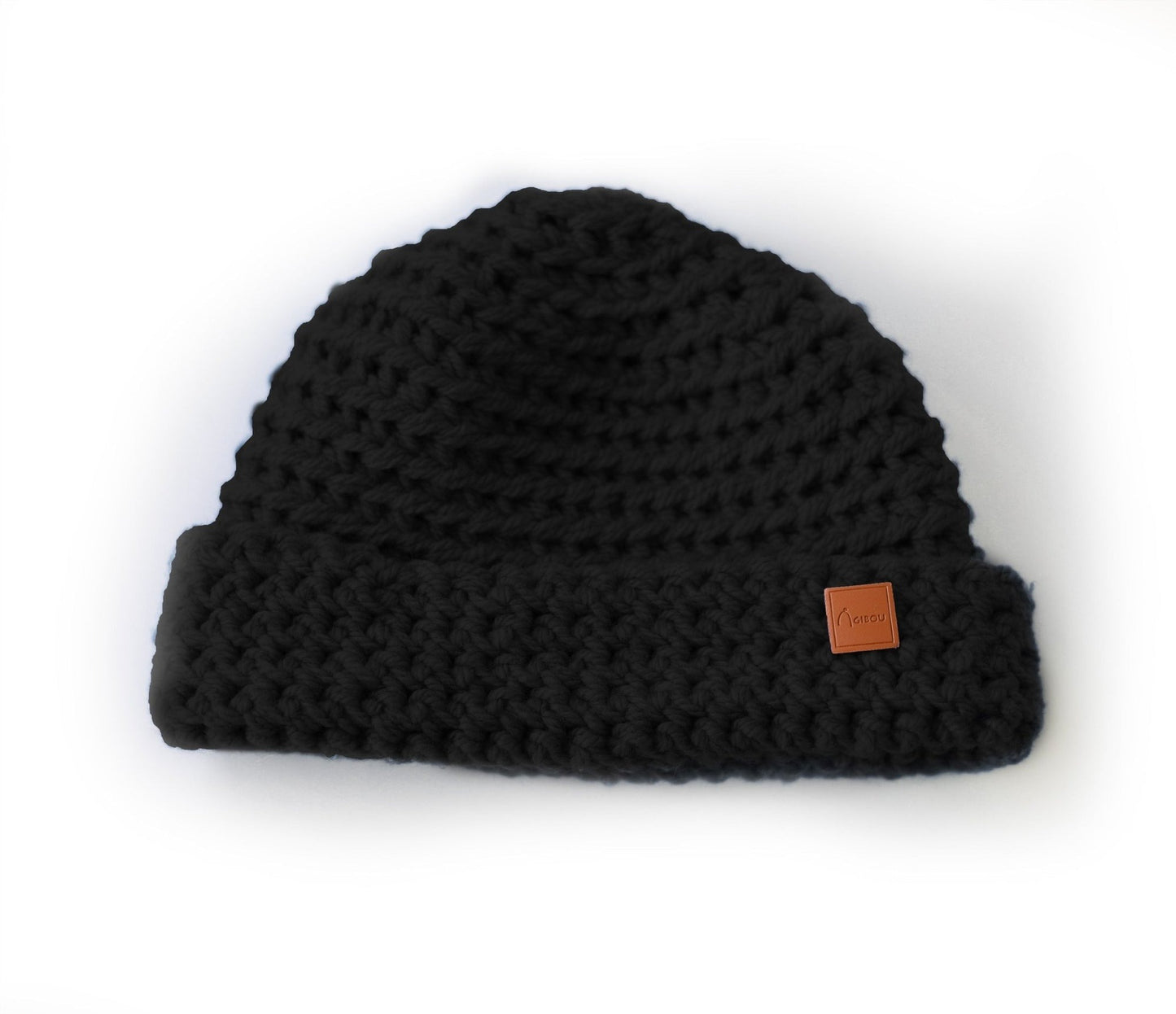 Bonnet à grosse maille tricoté à la main avec le bord retroussé et une petite étiquette en cuir marron avec le logo de la marque et Gibou marqué dessus. 