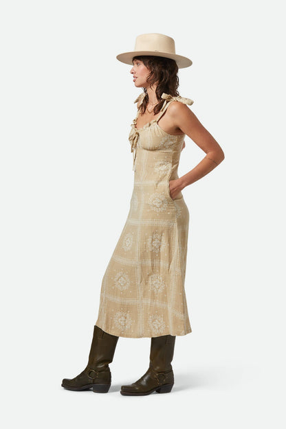 Vue de côté mettant en valeur la silhouette longue et fluide de la robe beige
