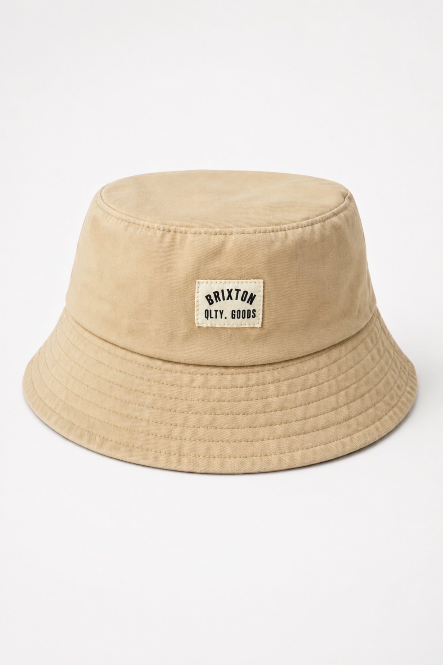 Chapeau bob Woodburn beige présenté de face, avec étiquette tissée Brixton, bord court matelassé et tissu 100 % coton.