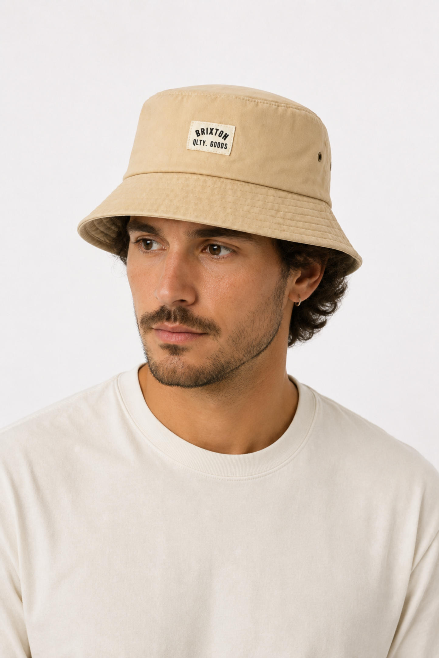 Homme portant le chapeau bob Woodburn beige en coton, avec bord court, étiquette tissée et style vintage décontracté.