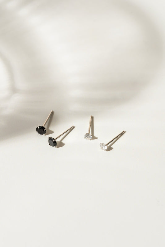 Ici on peut voir le modèle zeta qui est une paire de clous d'oreilles en argent .925 avec au boit des zircons noirs de 4 mm ou des zircons en cristal de 3 mm. L'arrière-plan est un fond blanc. 